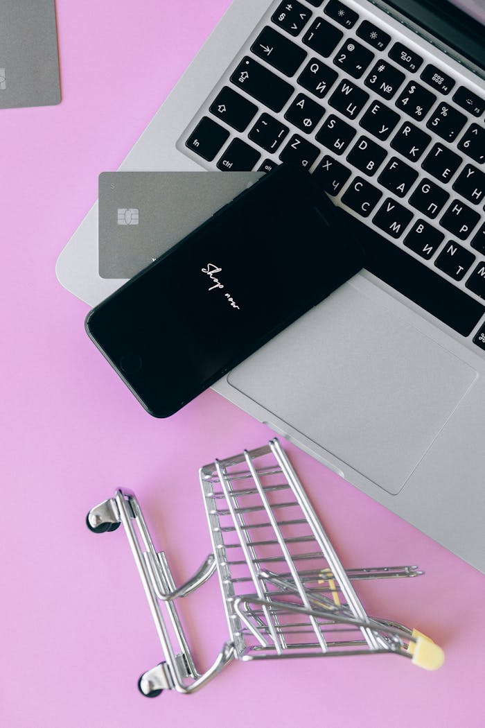 Laptop with smartphone and shopping cart, symbolizing online shopping and ecommerce.